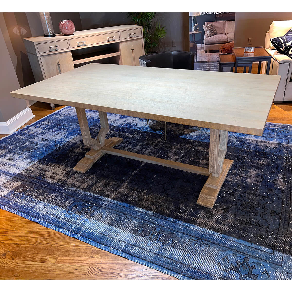Modern trestle dining table in furnished room setting.