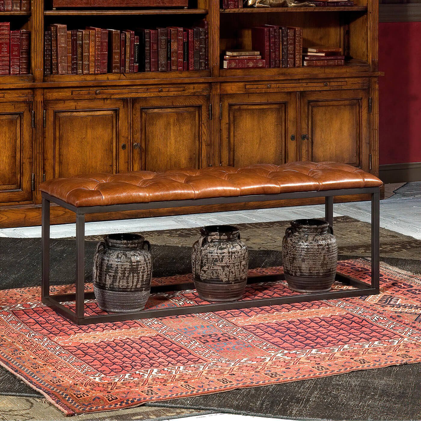 Leather bench in front of wooden cabinet and books.