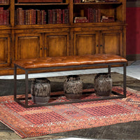 Leather bench in front of wooden cabinet and books.
