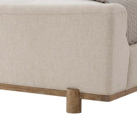 Modern upholstered bed corner with wooden leg detail.