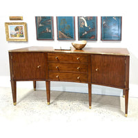 Modern walnut sideboard in room, decorated with artwork and bowl.
