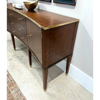 Side view of walnut sideboard, brass trim, wooden bowl.