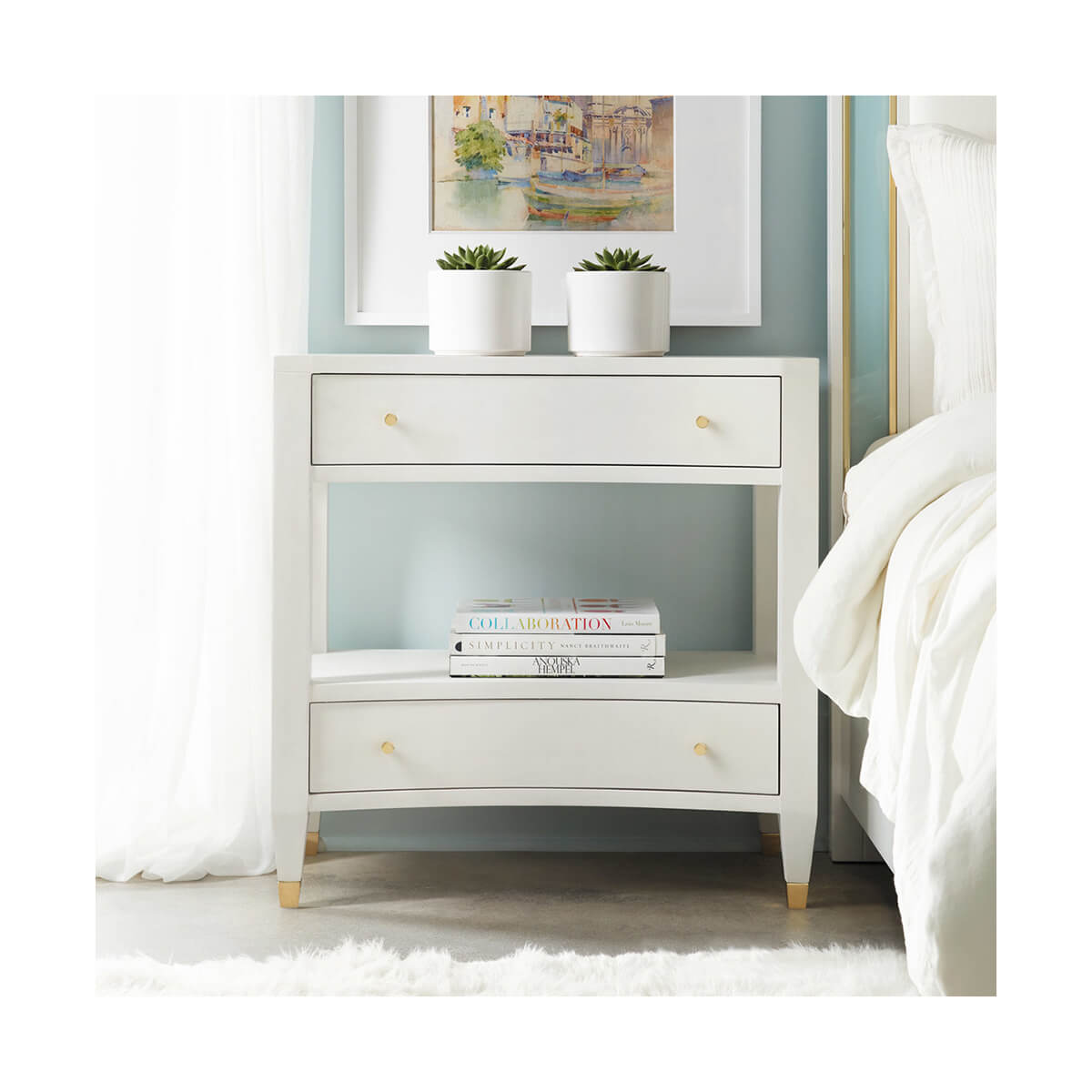 Nightstand styled in bedroom with books and plants.