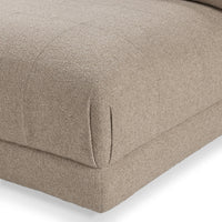 Close-up of beige modular sectional seat cushion with stitched corner and upholstered base