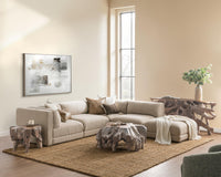 Beige modular sectional styled with neutral pillows, a draped throw and sculptural wood tables