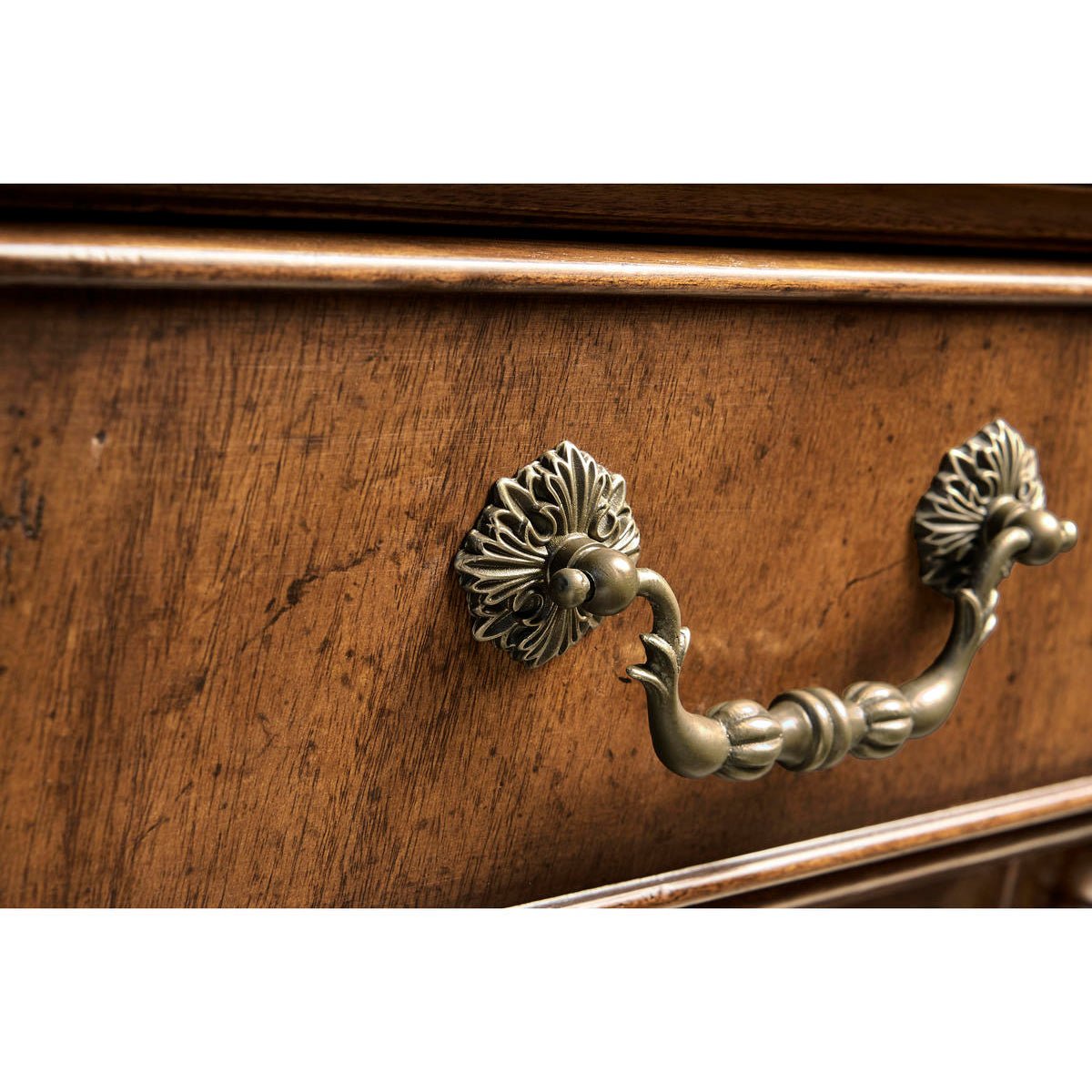 Close-up of antique drawer handle on walnut sideboard.