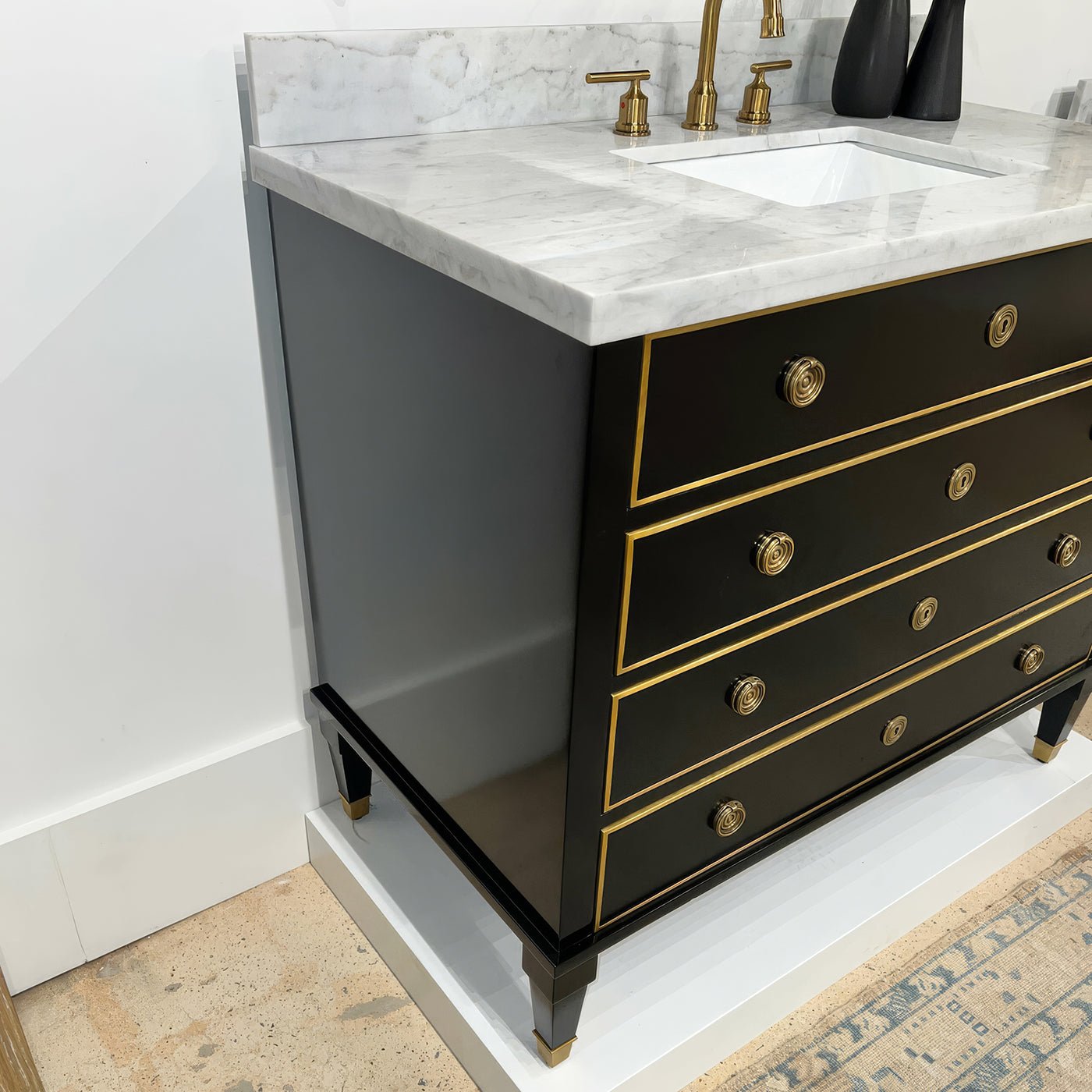 Side view of black marble top vanity against white wall.