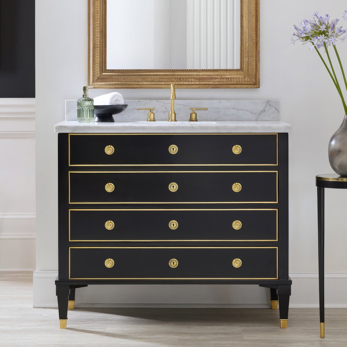 Black vanity with mirror and gold accents in bathroom.