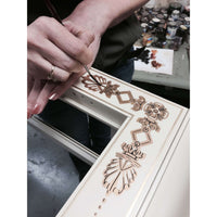 Hand-painting decorative details on curio cabinet panel.