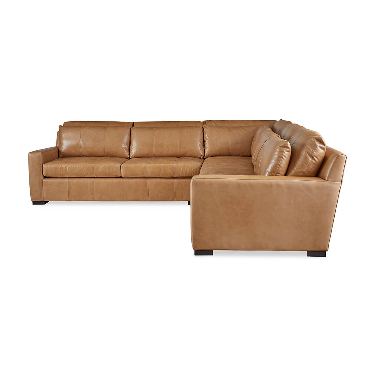 Angled view of tan leather sectional sofa.