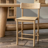 Light oak counter stool beside a wood counter table and storage cabinet