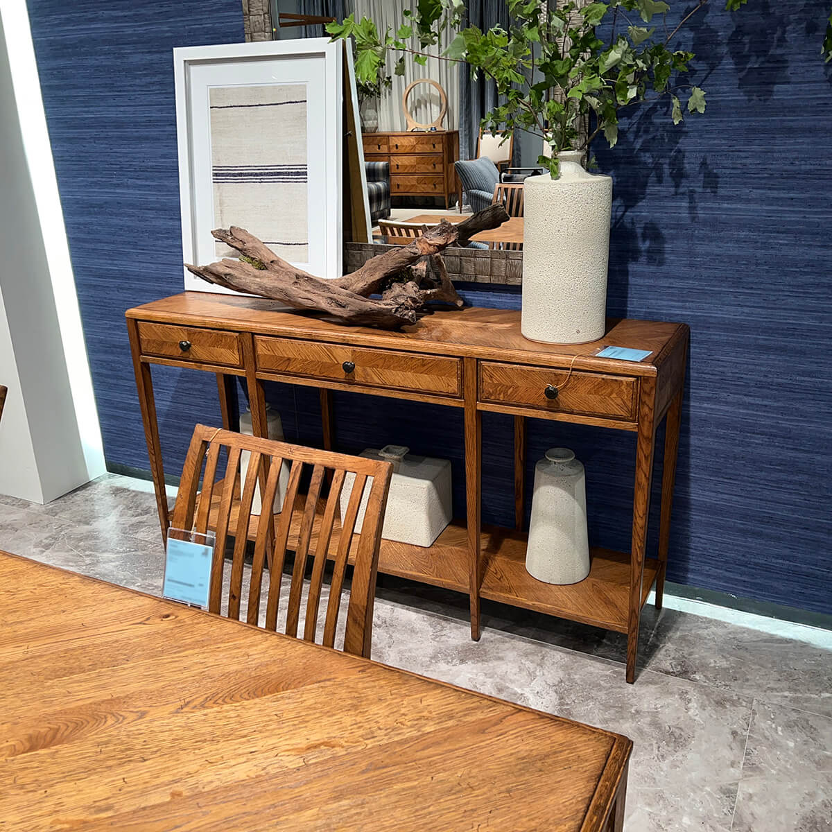 Oak console table with decor, against blue wall.