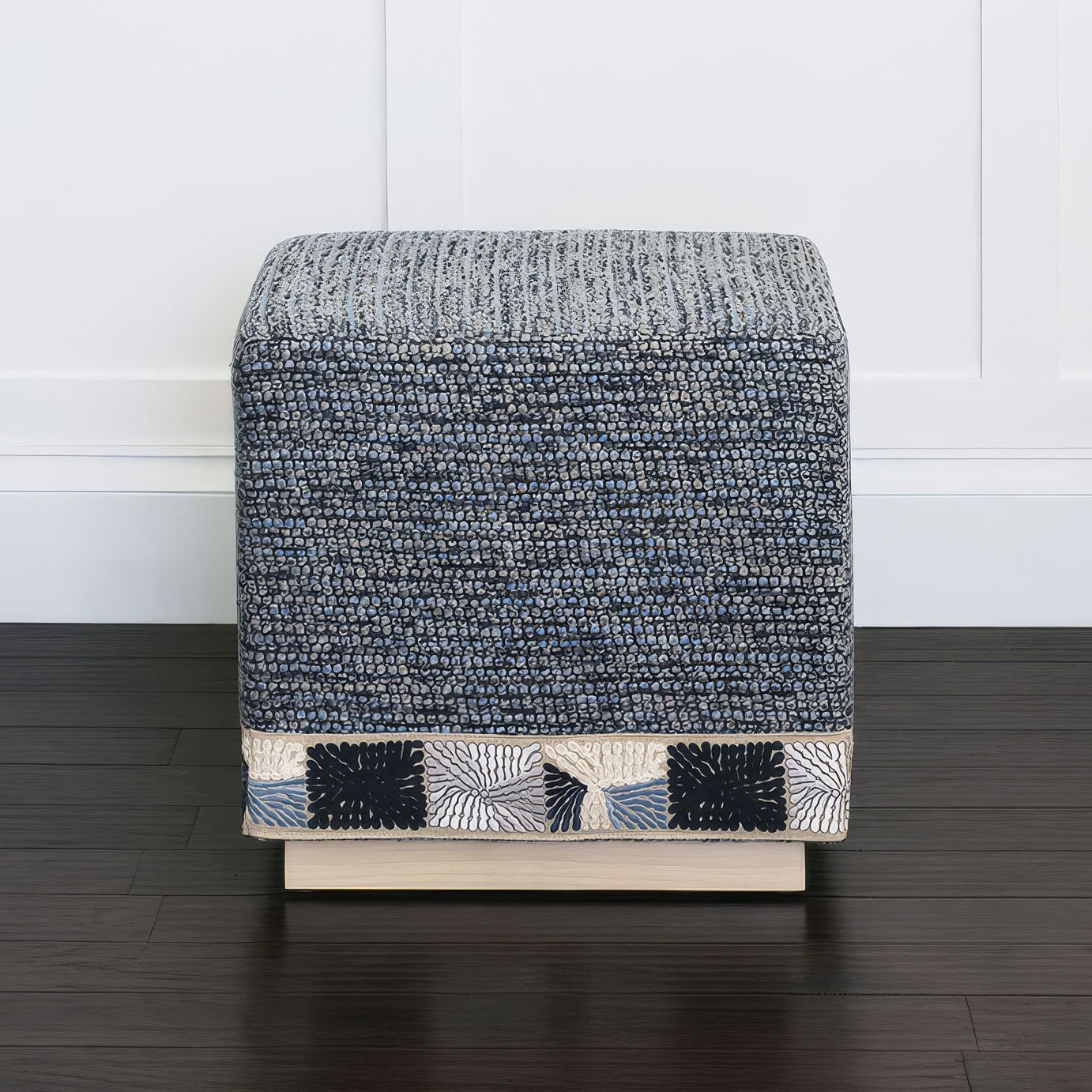 Side view blue cube ottoman, white walled background.