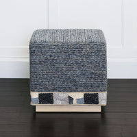 Side view blue cube ottoman, white walled background.
