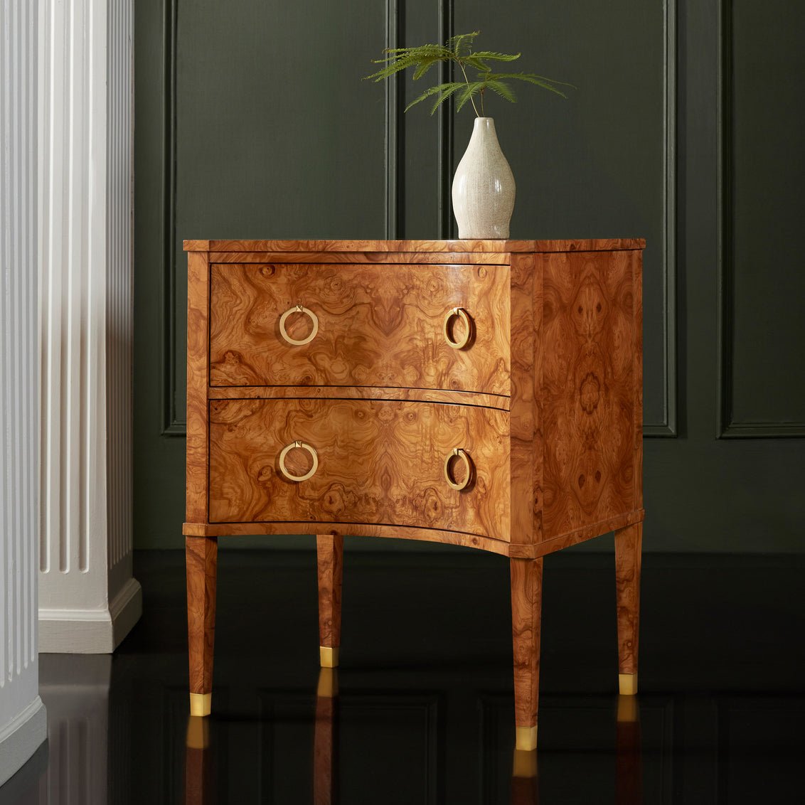 Nightstand in room, two drawers, decorative vase on top.