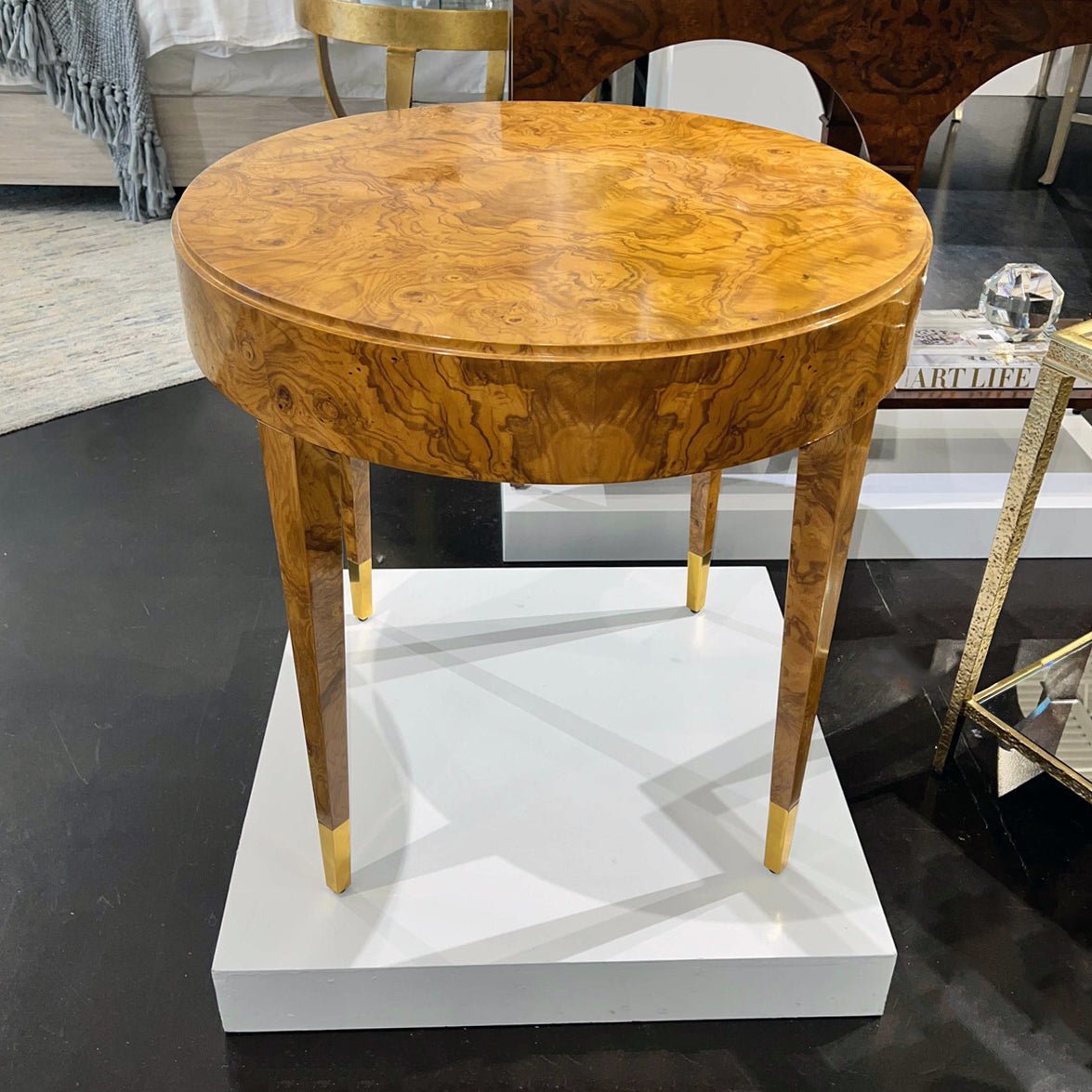 Olive wood side table on a white platform.