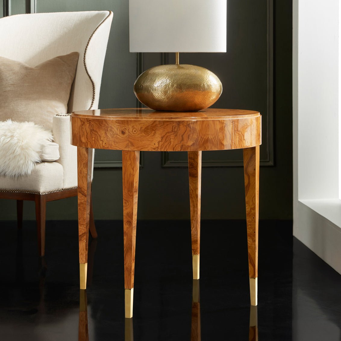 Side table with brass-tipped legs beside a chair.
