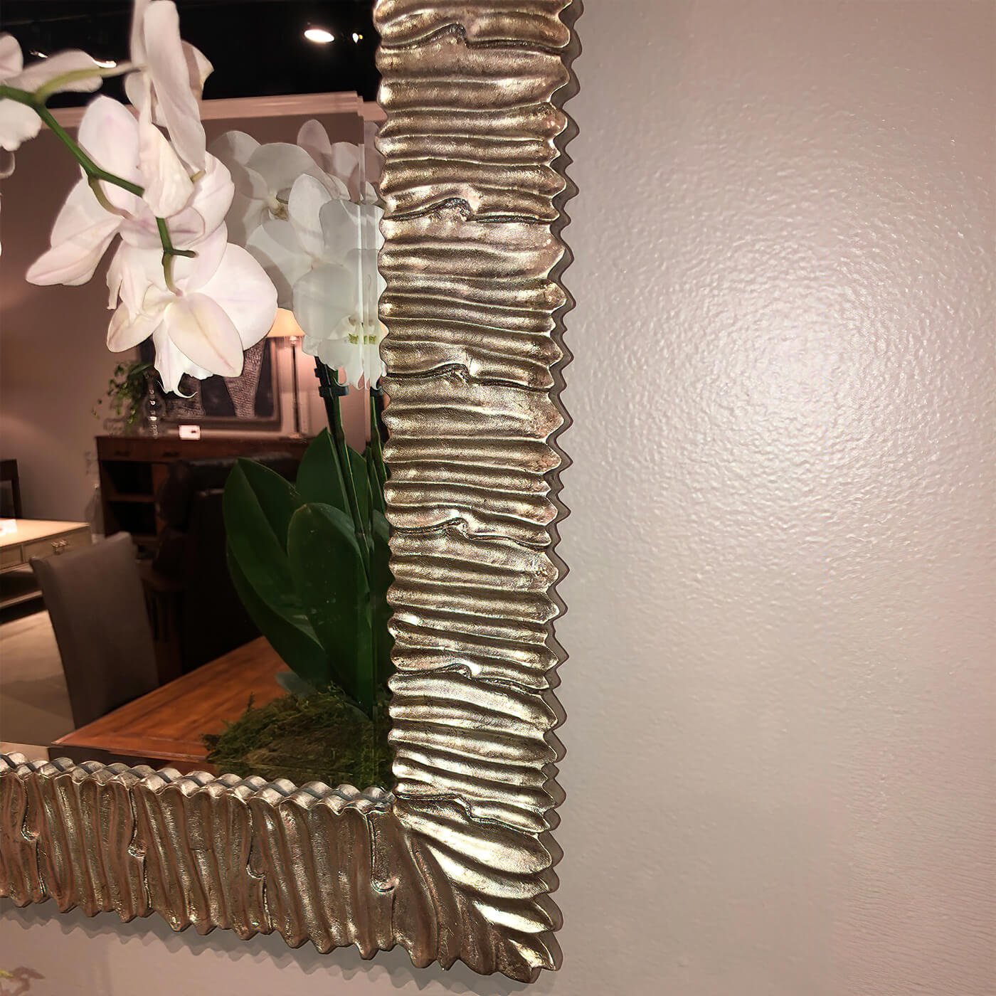 Silver gilt mirror with floral reflection, detailed corner.