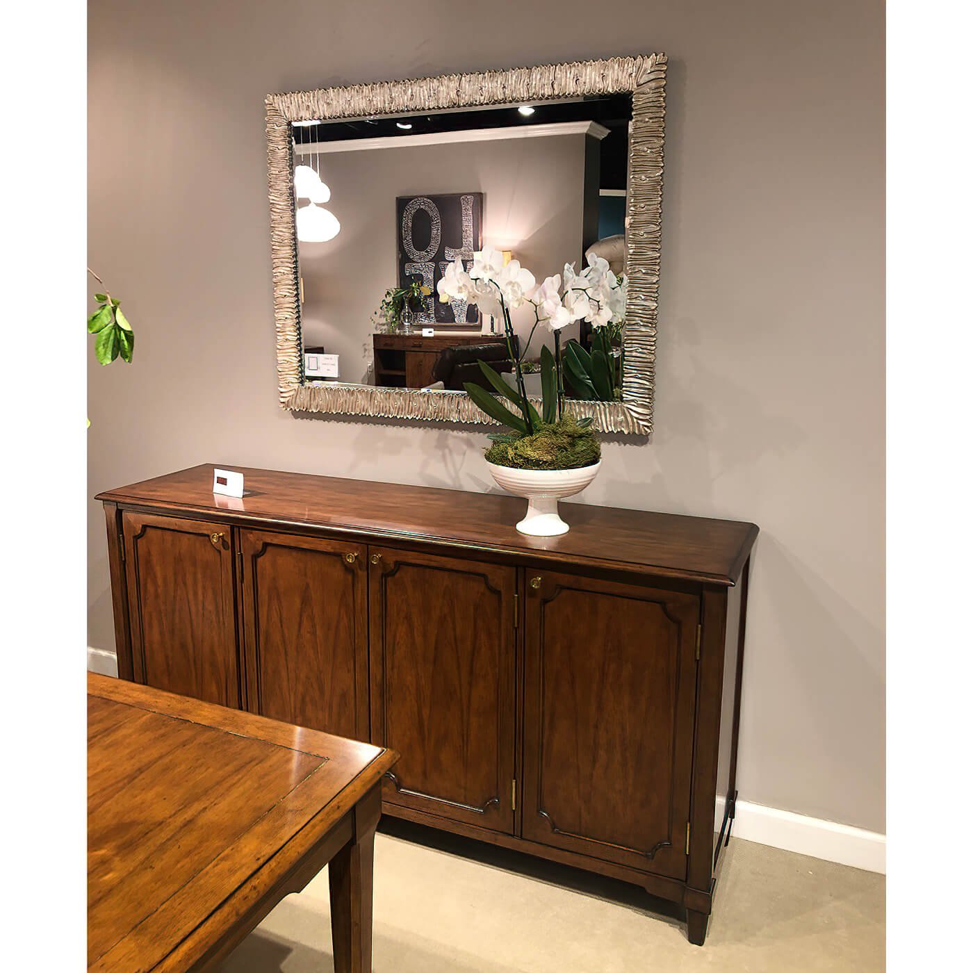 Silver mirror above wooden cabinet, elegant home decor.