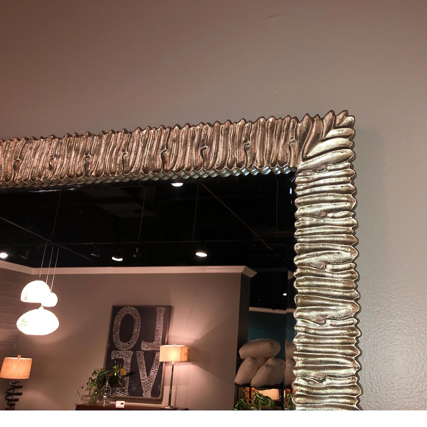 Close-up of textured edge on wall-mounted silver mirror.