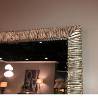 Close-up of textured edge on wall-mounted silver mirror.