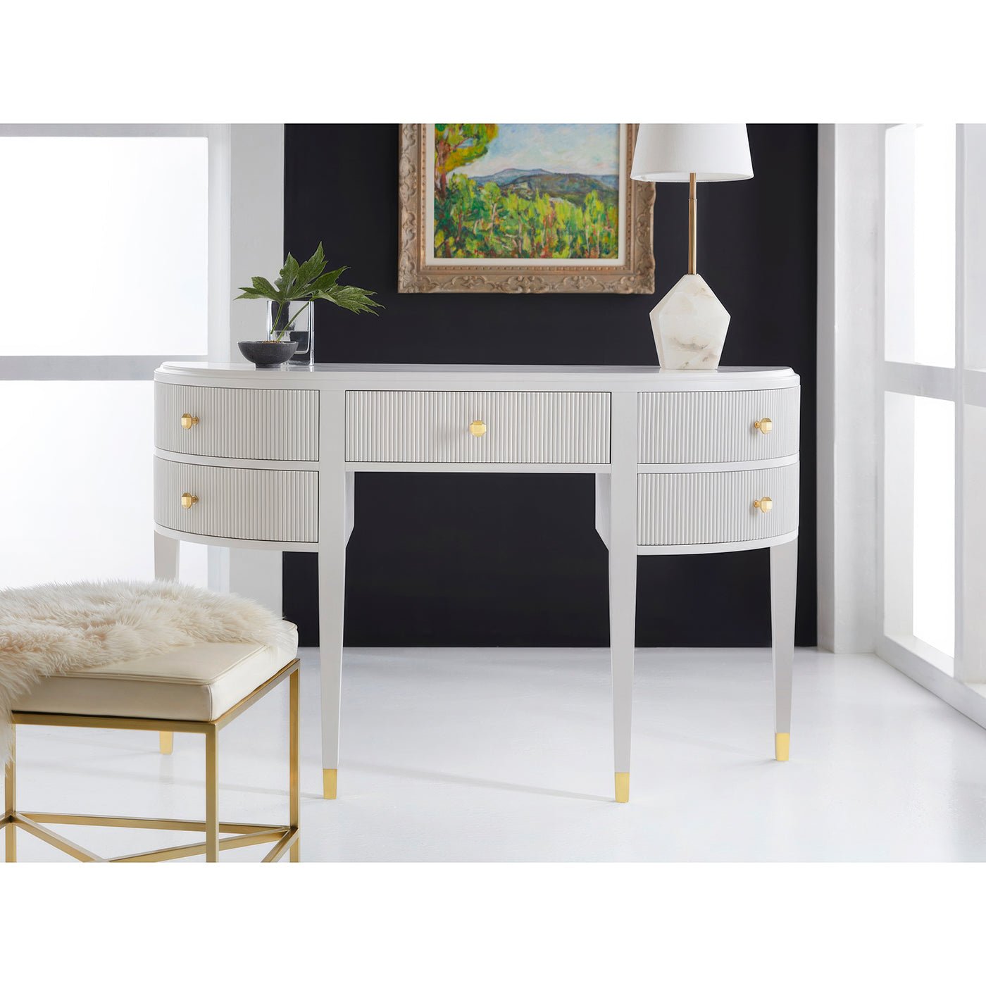 Art deco console in styled room with artwork and lamp.