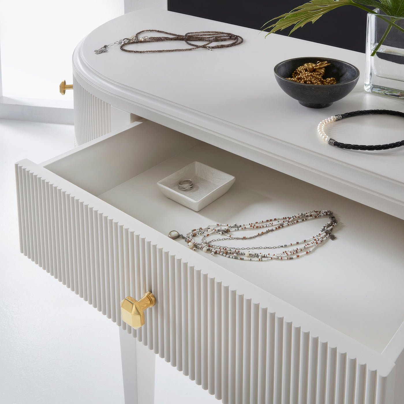 Upper drawer of console vanity with jewelry and decor.
