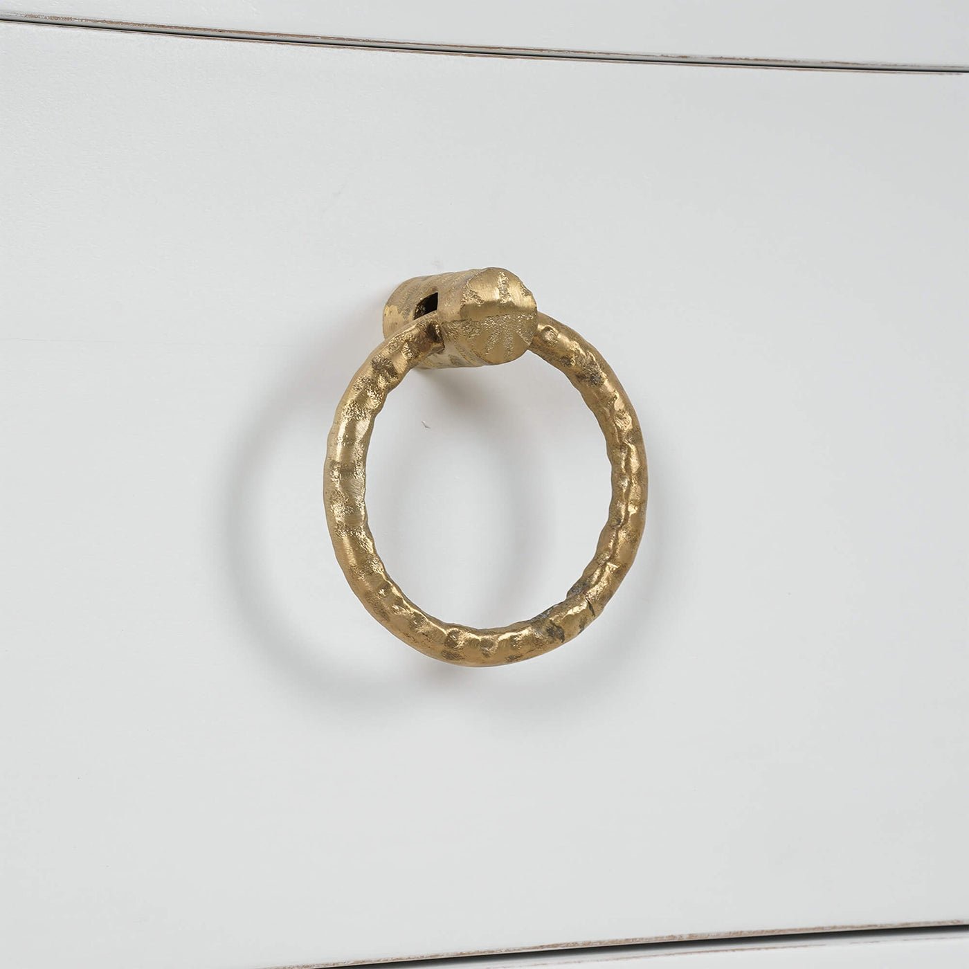 Gold handle detail on white nightstand drawer.