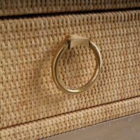 Close-up of nightstand brass ring handle and rattan texture.