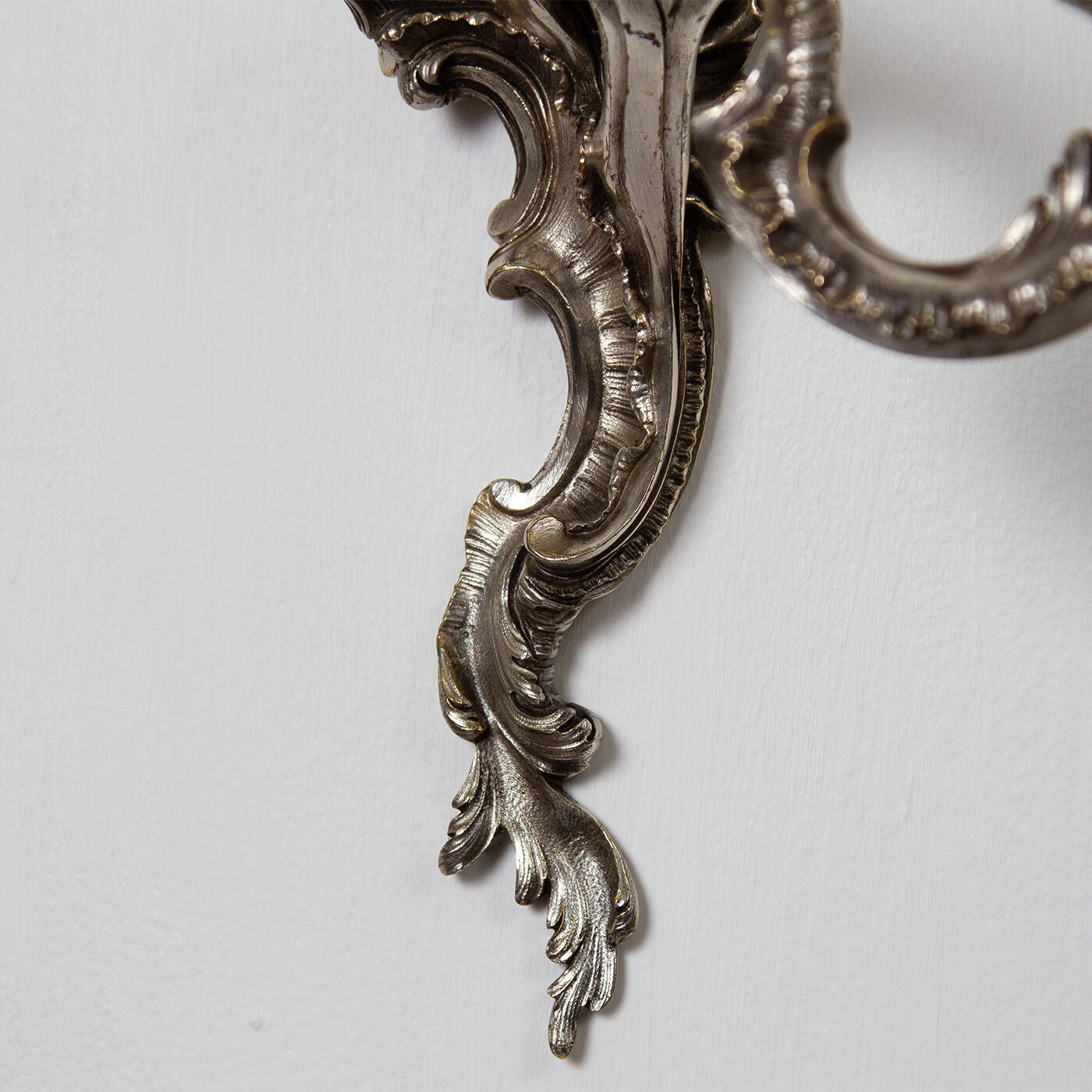 Base detail of graceful French Chinoiserie sconce, scrollwork.