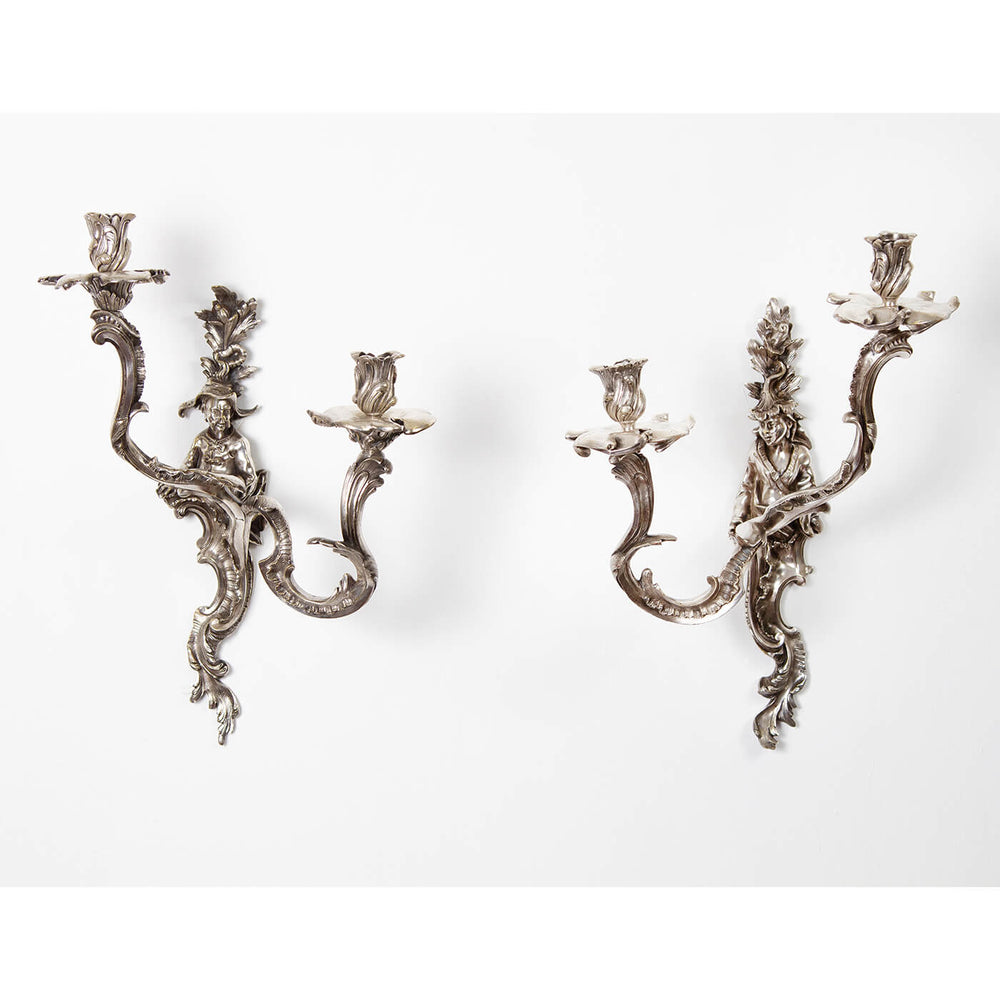 Pair of ornate French Chinoiserie sconces on white wall.
