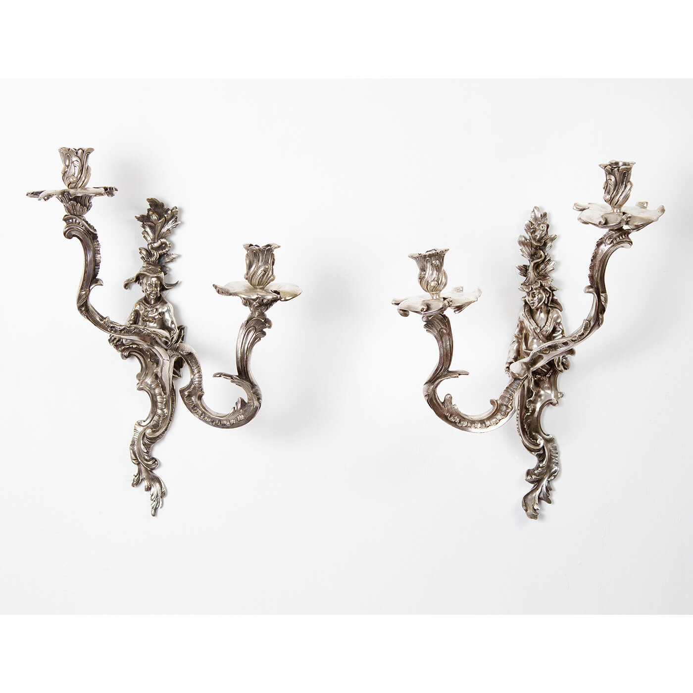 Pair of ornate French Chinoiserie sconces on white wall.