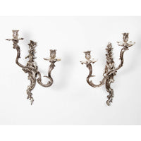 Pair of ornate French Chinoiserie sconces on white wall.