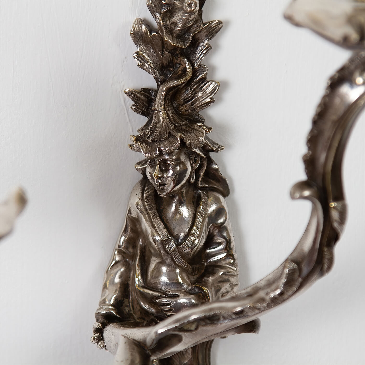 Detailed figure on French Chinoiserie sconce, artistic craftsmanship.