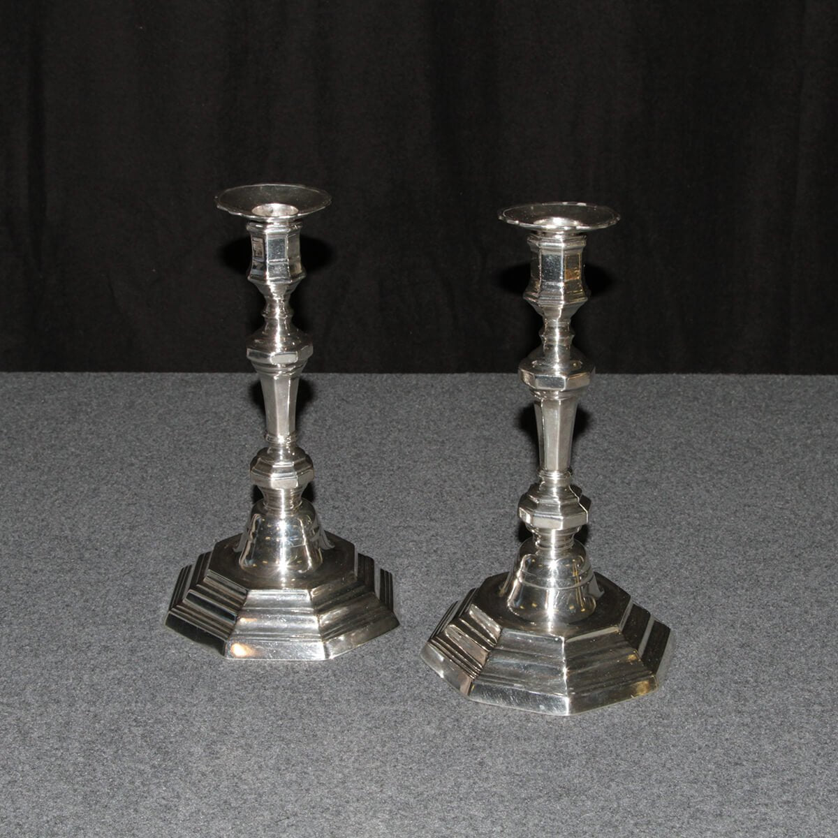 French Louis XVI candlesticks on dark background, side view.