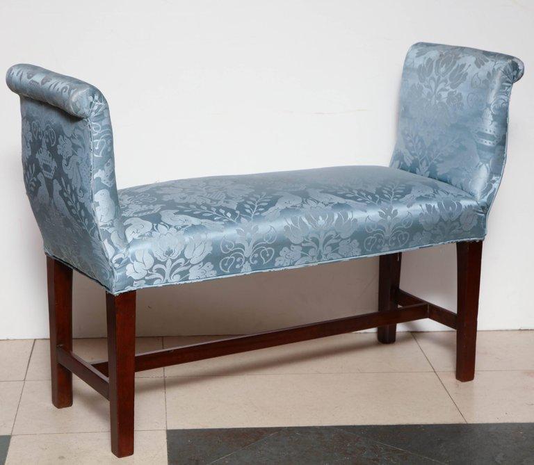Single blue upholstered mahogany bench, angled side view.