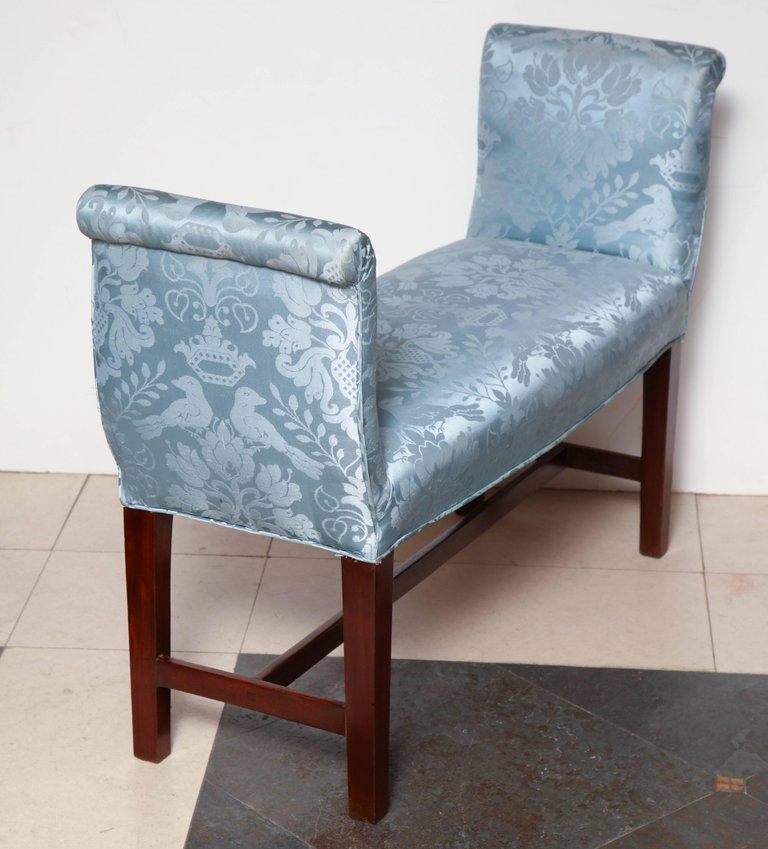 Blue upholstered bench showing detailed floral pattern, rear side.