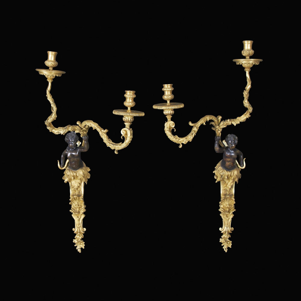 Pair of Regence bronze two-arm sconces on black.