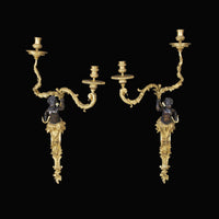 Pair of Regence bronze two-arm sconces on black.