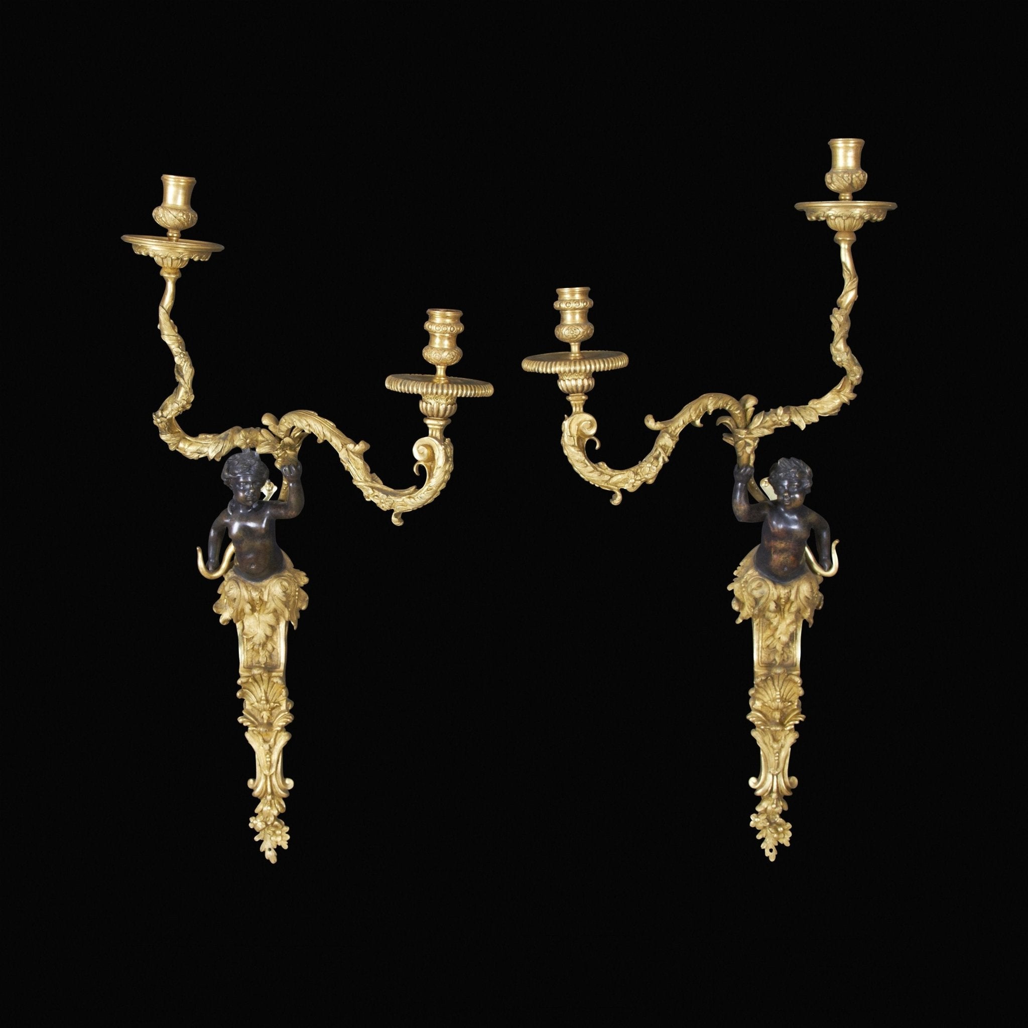 Pair of Regence bronze two-arm sconces on black.