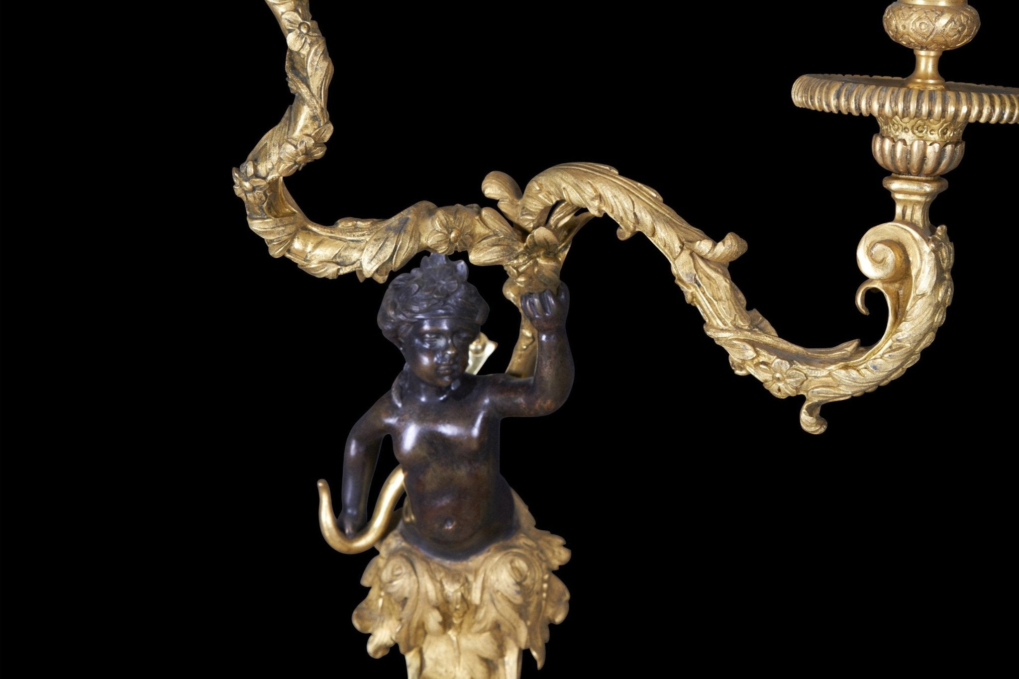 Detailed view of bronze sconce cherub and ornate arm.