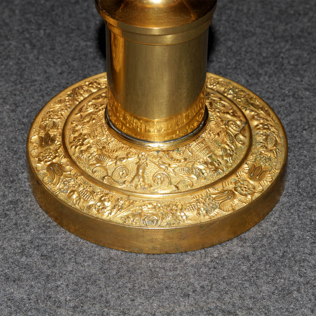 Close-up of candlestick base with floral engravings.