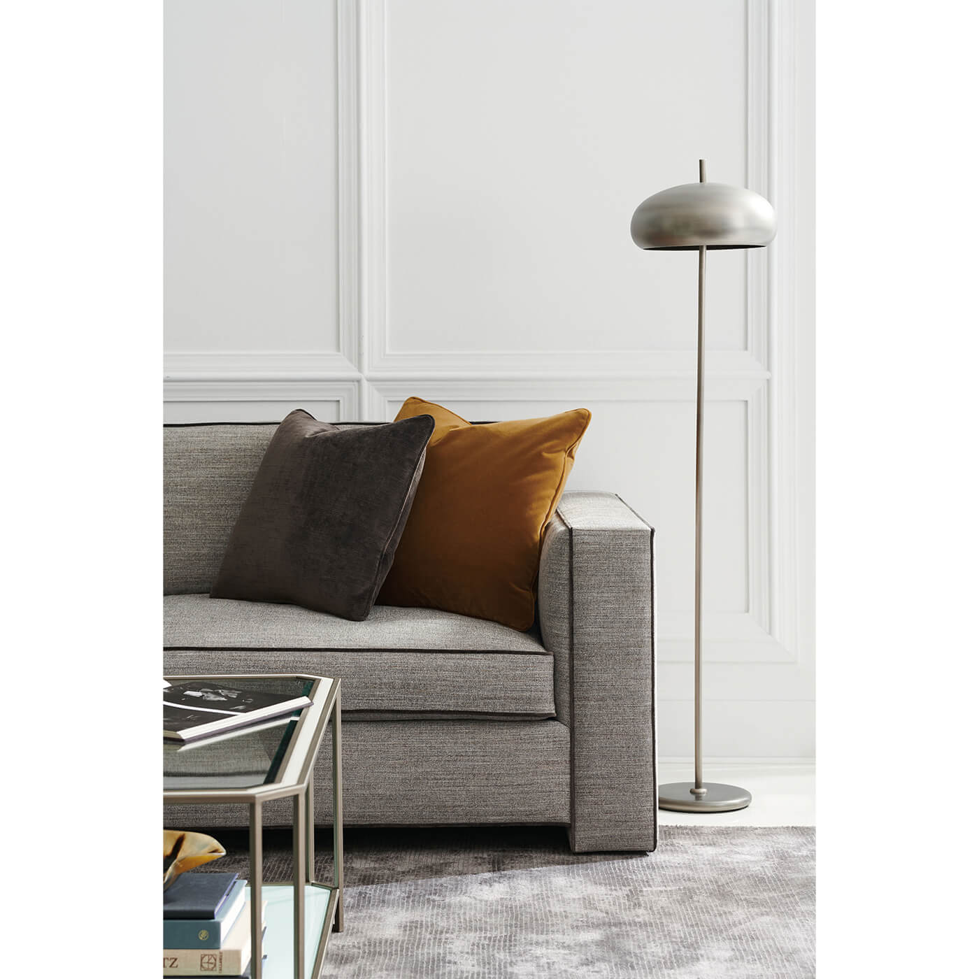 Sofa with pillows next to modern floor lamp.