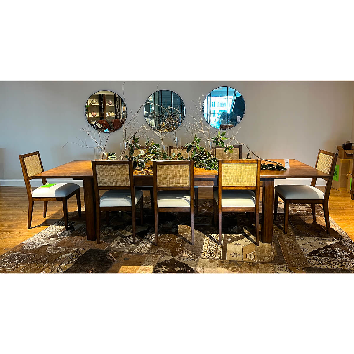 Extended Parsons table with chairs, dining setup, mirrors behind.