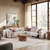 Gray power reclining sectional styled beside tall windows with a round wood coffee table and accent pillows
