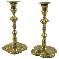 Pair of Queen Anne brass candlesticks on display.