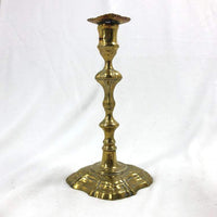 Single Queen Anne brass candlestick against white background.