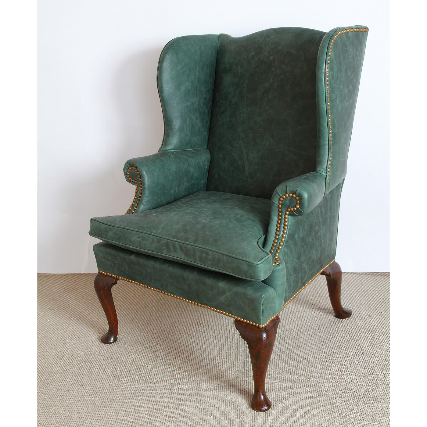 Wingchair angled view, leather upholstery, and decorative studs.