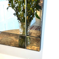 Close-up of mirror corner showing detail, reflects flowers.
