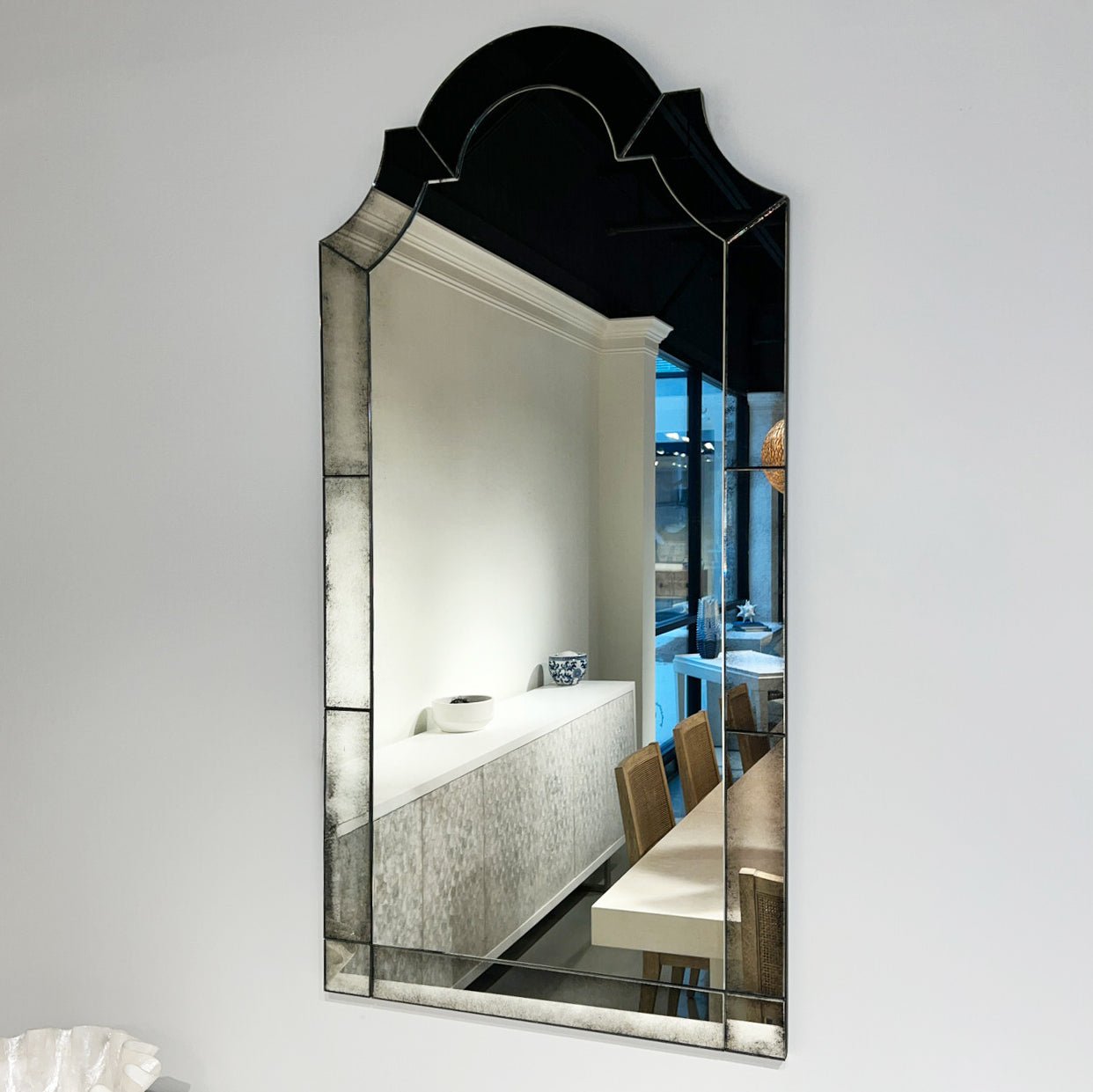 Arched mirror reflecting modern dining room interior.